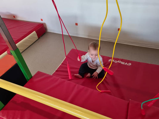 Photographie d'un bébé, dans une salle de Gym adaptée aux bébé pour la motricité libre